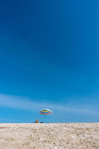 Parasol at beach against blue sky
