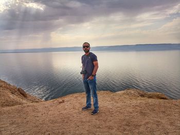 Portrait of man standing by lake during sunset