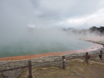 Scenic view of geothermal lake against cloudy sky