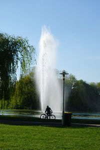 Man with bicycle on grass against sky