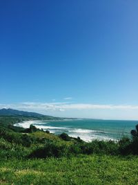 Scenic view of field by sea against sky