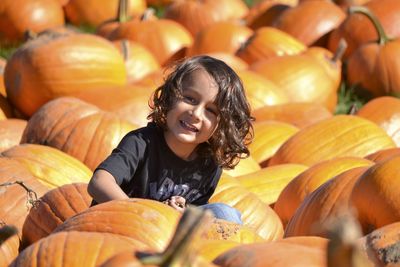 Full length of a smiling girl with pumpkins in background