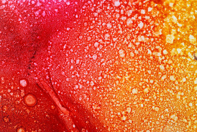 Full frame shot of wet glass against orange background