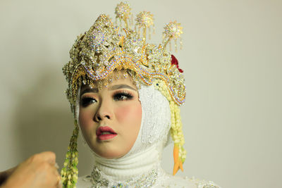 Portrait of young woman in traditional clothing standing against white background