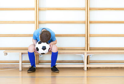 Boy with soccer ball sitting on bench