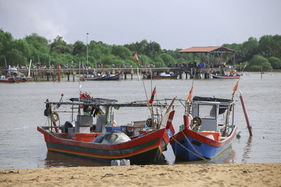 Fishing boats moored on beach against sky