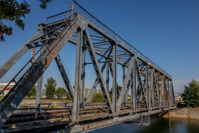 Low angle view of bridge over river against blue sky