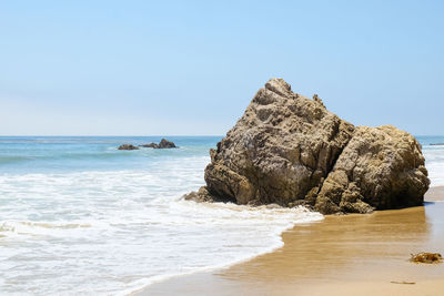 Rocks on beach against clear sky