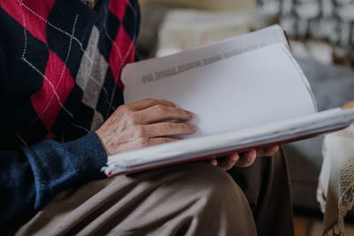Midsection of senior woman reading book in home