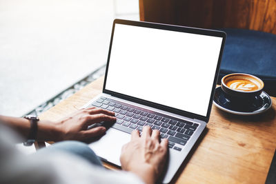 Cropped hands using laptop on table