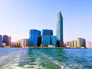 Sea by modern buildings against clear sky