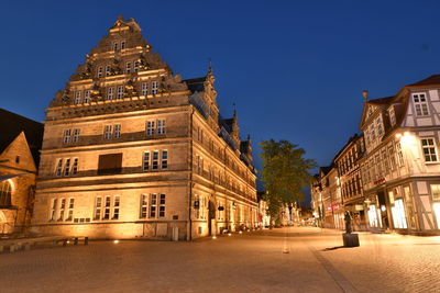 Street amidst buildings against clear sky at night