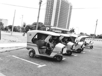 Side view of vehicles on road against buildings