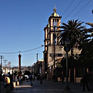 Road leading towards buildings against clear sky