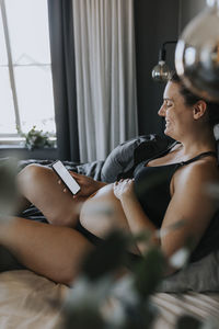 Pregnant woman relaxing in bed and using phone