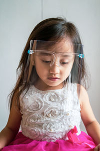 A toddler girl wearing the face protection shield. a safety corona mask during covid-19 pandemic.