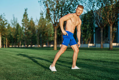 Portrait of shirtless man exercising on field