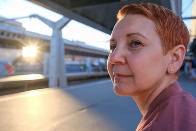 Woman looking away sitting at railroad station platform