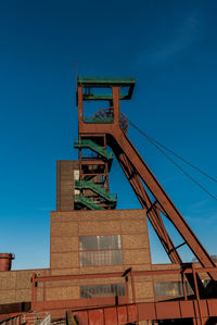 Low angle view of crane against blue sky