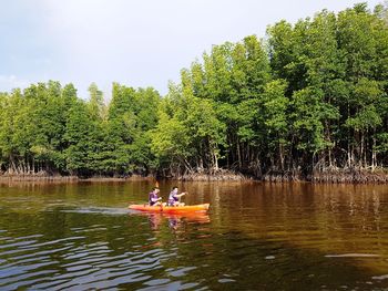 People on boat in lake against sky