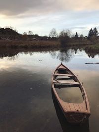 Boat moored in lake against sky