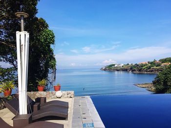 Swimming pool by sea against sky