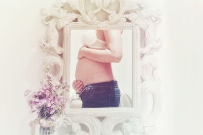 Midsection of person holding flower standing against wall