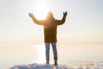 Full length of man standing at beach against sky during sunset