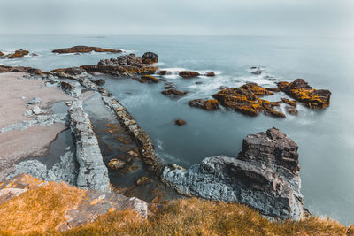 Scenic view of rocks in sea against sky