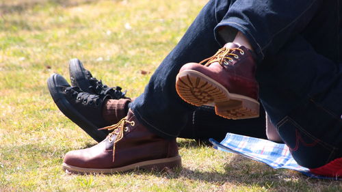 Low section of man holding shoes on field