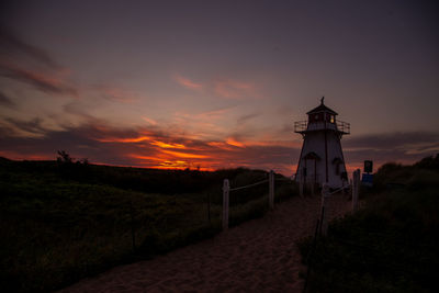 Lighthouse at beach against sky during sunset