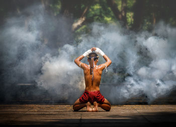 Full length rear view of shirtless warrior in forest