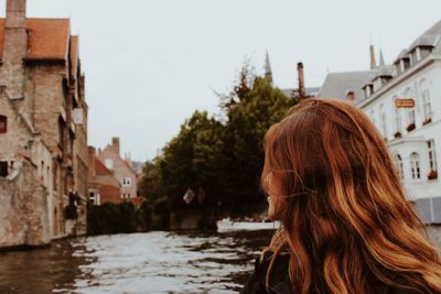 Woman looking away while sitting in boat on canal