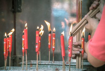 Cropped hands burning incense sticks