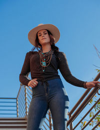 Low angle view of woman standing against clear blue sky