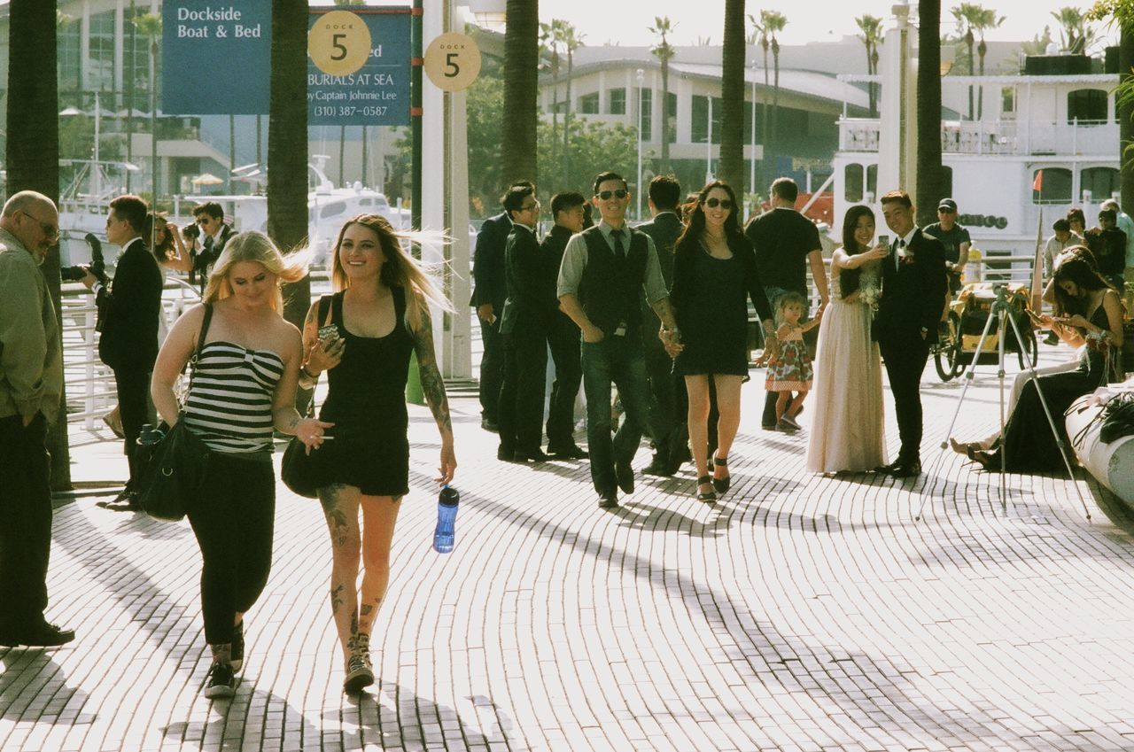 person, men, walking, lifestyles, large group of people, building exterior, city, architecture, street, built structure, city life, full length, leisure activity, rear view, standing, togetherness, casual clothing, day, sidewalk