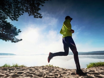 Sports man on the beach runs side by the sun, morning training. soul welcomes the dawn or sunset.