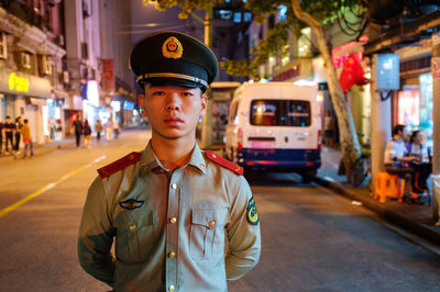 Portrait of young man standing on city street at night