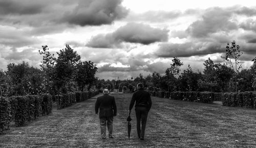 Rear view of people on road against sky