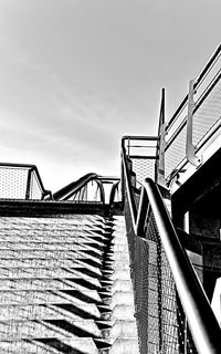 Staircase by bridge against sky in city