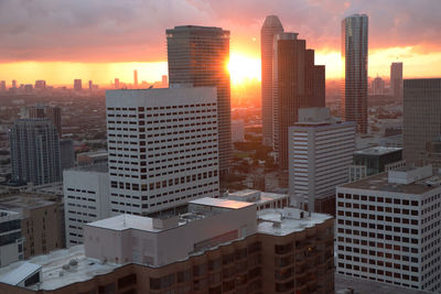 Modern buildings in city against sky during sunset