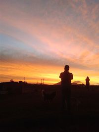 Scenic view of landscape against cloudy sky at sunset