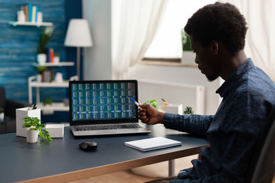 Side view of businessman pointing at laptop