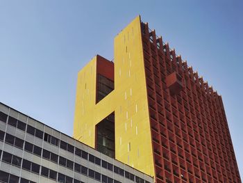 Low angle view of yellow skyscraper against clear sky