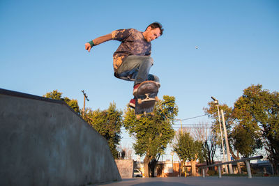 Low angle view of man skateboarding against clear sky