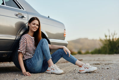 Young woman sitting on car