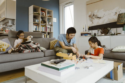 Siblings assembling robotic model sitting in living room at home