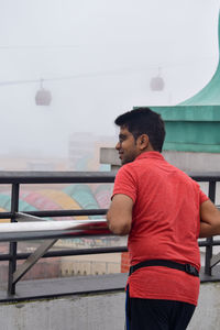 Rear view of man standing by railing