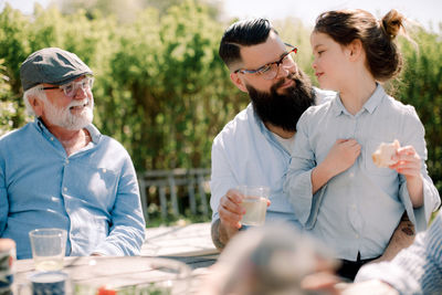 Smiling senior man looking at family having food at patio