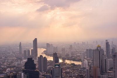 Modern buildings in city against sky during sunset